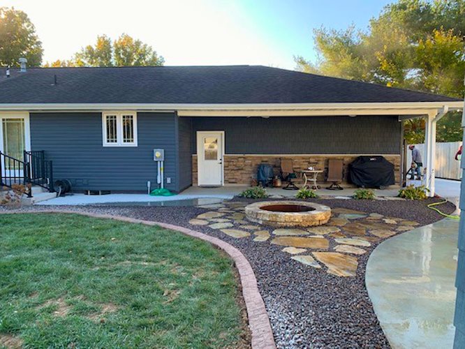 blue house with a professional firepit, pavers, and concrete edging.